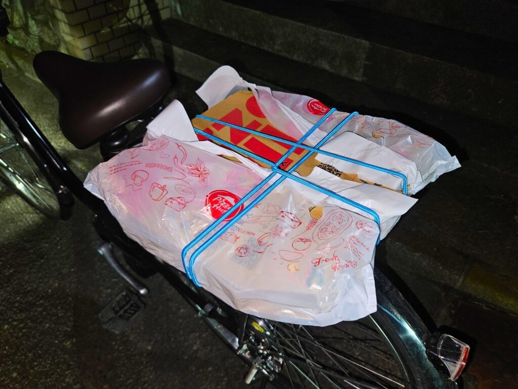 100均の自転車ロープでピザの箱を自転車の荷台に固定した図